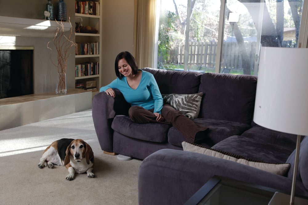 Woman sitting on couch with day laying next to couch